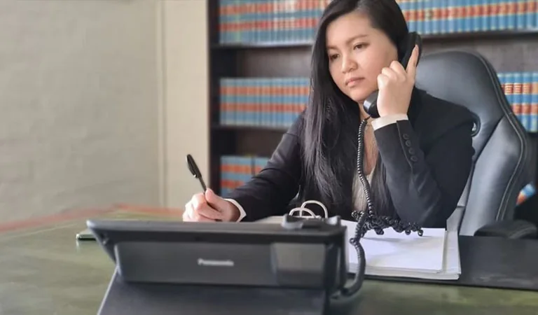 Một nữ luật sư ghi chép trong khi nói chuyện điện thoại tại bàn làm việc